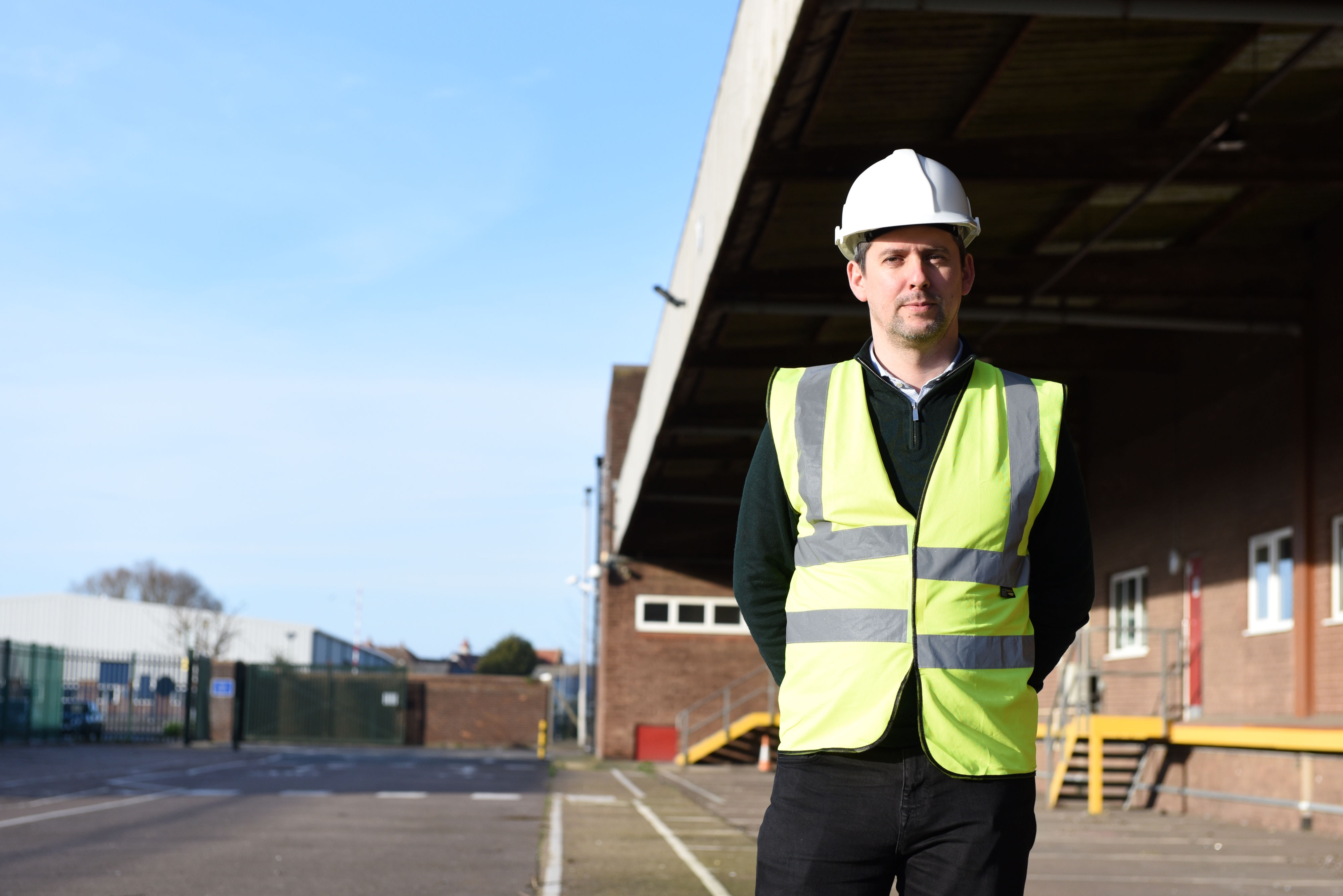 Cllr Chris Chambers stands outside the current site in Ipswich dressed in high vis and a white hard hat
