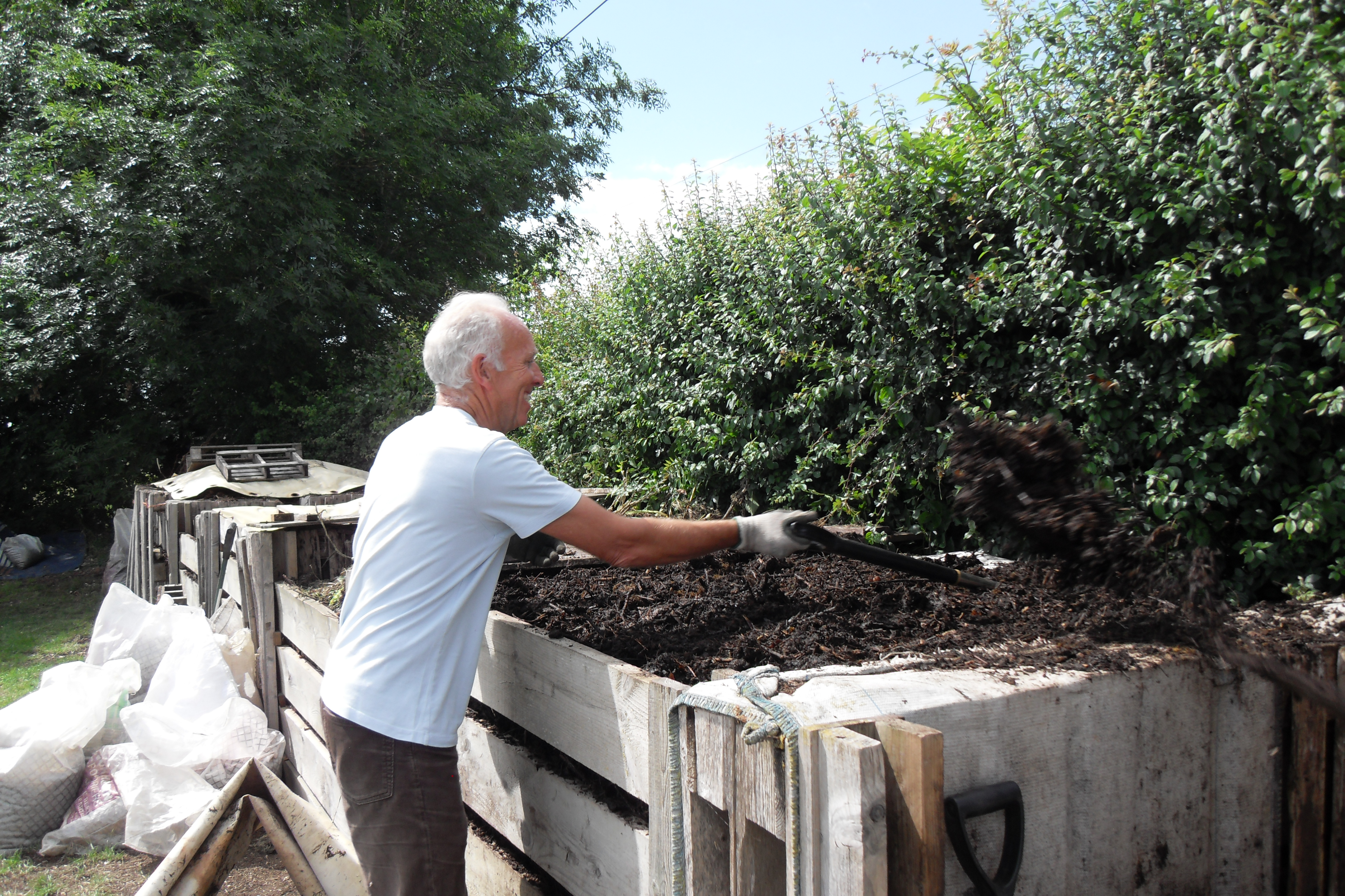 Person turning compost in a compost bin. 