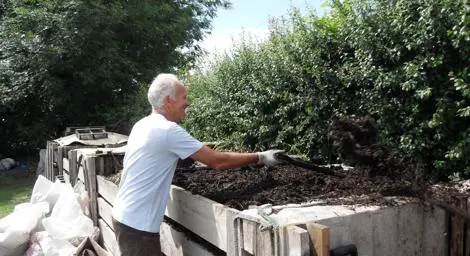 Person turning compost in a compost bin. 
