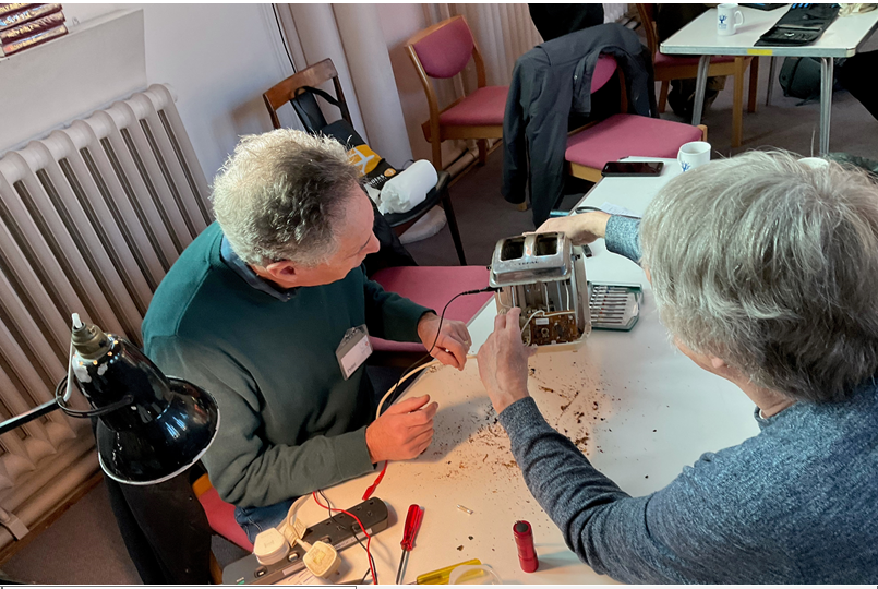 Two people rebuilding a metal toaster