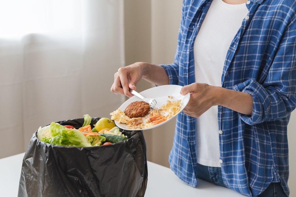 Person scraping food into a bin. 