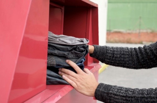 Hands pushing a bundle of clothes into a clothes bank